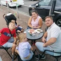 Family enjoying food outside The Little Blue Hut