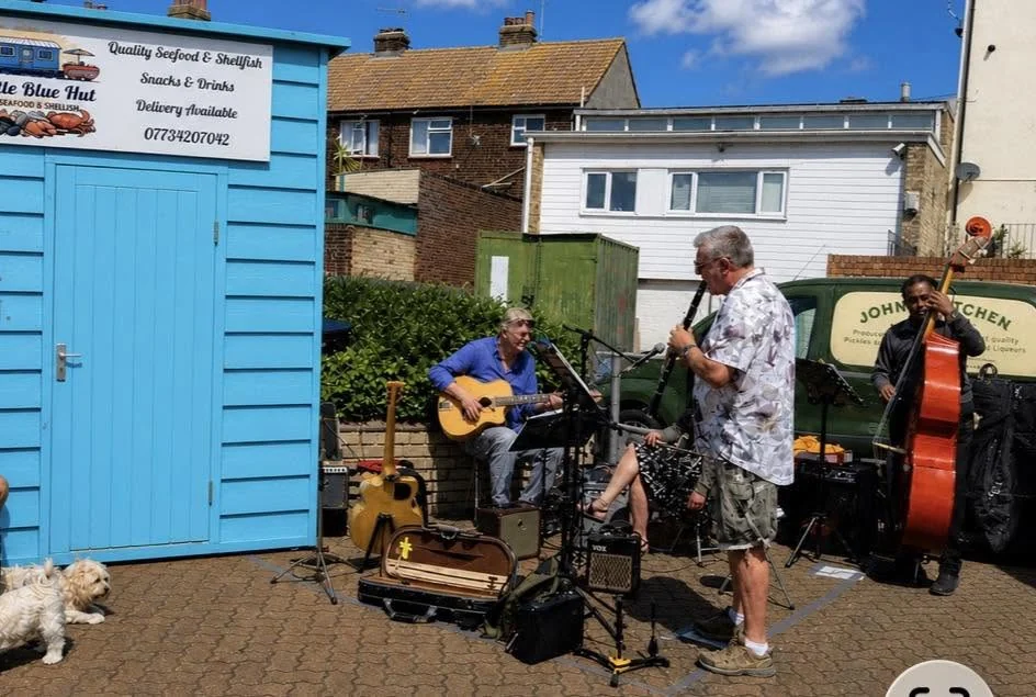 Live musicians performing beside The Little Blue Hut